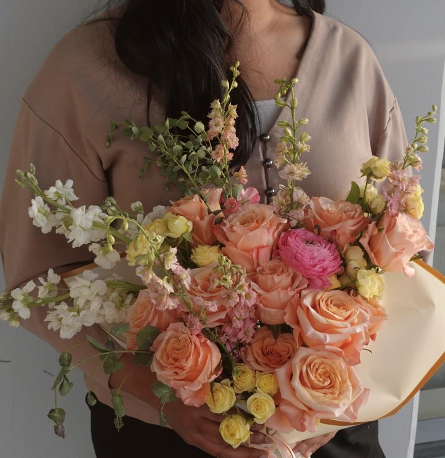 Hand-tied bouquet with peach, blush, and pink blooms.